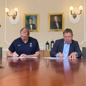 People signing documents at a meeting table